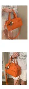 Vista dettagliata della borsa a tracolla arancione con design morbido e ciondolo in peluche.