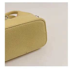 Yellow textured leather bucket bag detail, women's minimalist daily fashion handbag.