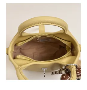 Top-down detail view of the yellow leather bucket bag interior, zipper pocket and lining.