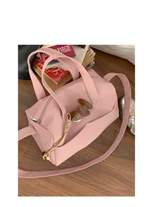 Borsa a spalla rosa in dettaglio, morbida pelle sintetica, doppi manici e ciondolo carino.