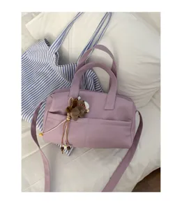 Dettaglio borsa a tracolla morbida viola, elegante borsa da lavoro con ciondolo grazioso.