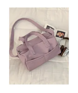 Vista dettagliata della borsa a cuscino morbida viola con doppi manici e cerniera lampo.