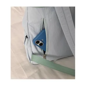 Primo piano della tasca con cerniera dello zaino in nylon azzurro con comodi spallacci.