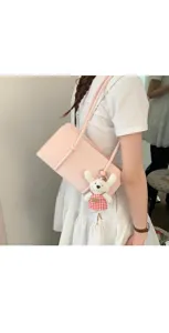 Close up detail of pink underarm shoulder bag with cute plaid dress plush pendant.
