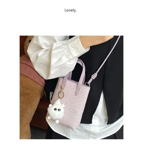 Detailansicht der stylischen violetten geflochtenen Mini-Eimer Tasche mit süßem Plüsch-Anhänger.