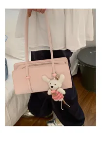 Close-up of a chic pink underarm shoulder bag featuring a cute plush rabbit charm.