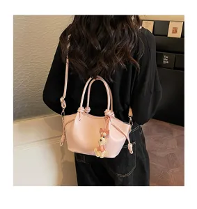 Détail de sac à main rose chic avec pendentif chiot mignon et poignée nouée élégante.