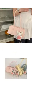 Detailed view of the stylish underarm shoulder bag showcasing fine leather texture and cute plush pendant.