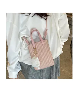 Rosa gewebte Mini-Eimer-Tasche Detailansicht mit süßem weißen Plüschanhänger und verstellbarem Riemen.