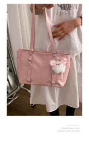 Pink tote shoulder bag detail view, featuring dual straps and cute plush bunny charm.