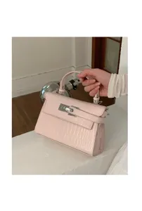 Nahaufnahme einer rosa Handtasche mit Krokodilprägung und silbernen Beschlägen.