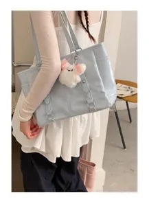 Detail view of a light blue commuter tote bag with cute plush keychain and double straps.