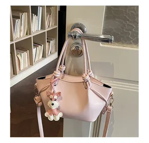 Vue détaillée du sac à main en cuir rose élégant avec poignées nouées et joli charm chien.