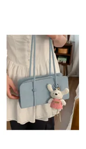Detailed view of the light blue shoulder underarm bag with double straps and cute plush charm.