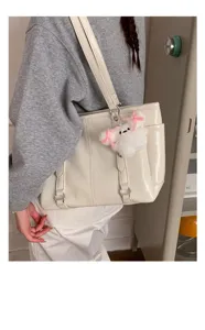 Detail view of the white patent leather commuter tote bag with cute plush keychain charm.