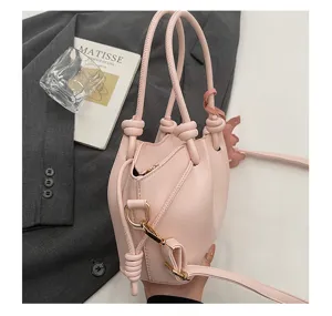 Vue de détail d'un sac à main seau rose élégant avec poignées nouées et quinzaine dorée.