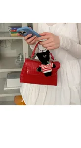 Nahaufnahme der roten Krokodilmuster Handtasche mit süßem Bärenanhänger und Schloss.