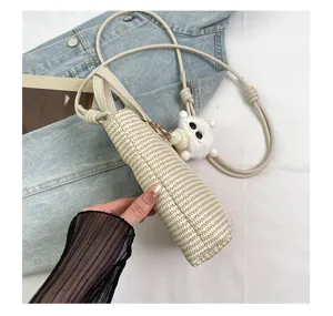 Nahansicht der kleinen gewebten Stroh-Eimer Tasche mit niedlichem Plüsch-Anhänger.