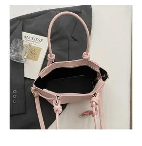 Détail de sac à main rose avec poignées nouées et texture en similicuir élégante et chic.