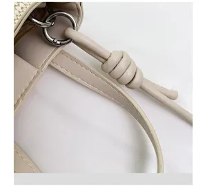 Detailansicht einer stylischen Mini Eimer Tasche mit Stroh Gewebe, Kunstlederriemen, Metallring.