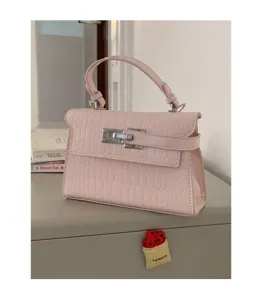 Detailaufnahme der eleganten rosafarbenen Kroko-Textur Kelly Handtasche mit Metallverschluss.