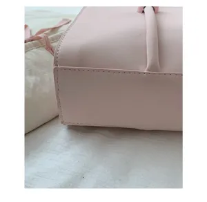 Pink minimalist handbag detail shot showing fine leather texture and neat stitching style.