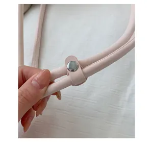 Detailed view of pink shoulder bag strap, smooth leather material with metallic snap button fastener.