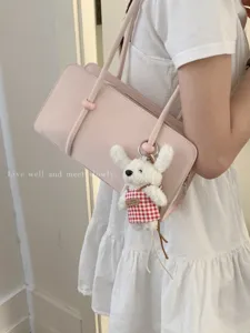 Minimalist pink underarm shoulder bag for women, chic bowling bag design with plush charm.