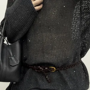 Close-up of a dark brown braided leather belt with small gold buckle worn with textured knit.