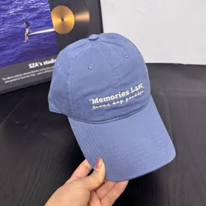 Detail shot of blue baseball cap with white embroidery text, casual style summer sun hat.
