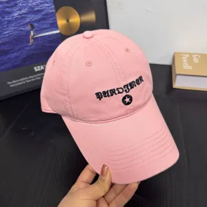 Detalle de gorra de beisbol bordada en rosa con letras goticas y estrella suave.
