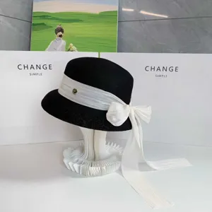 Dettaglio cappello cloche nero elegante con nastro fiocco bianco protezione solare.