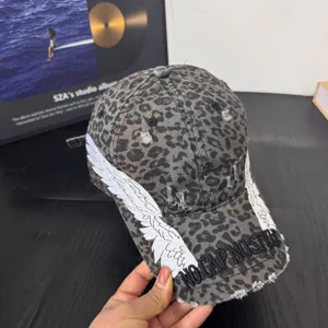 Leopard print baseball cap with white wings embroidery and distressed brim for streetwear style.