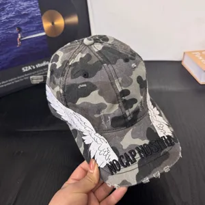 Camouflage baseball cap with white embroidered angel wings and stylish streetwear text design.