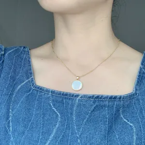 Primer plano detallado del collar con colgante de nácar de la Virgen María dorado.