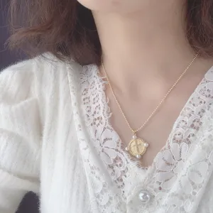 Close up of rhinestone cross pendant pearl coin necklace detail showing exquisite jewelry craftsmanship.