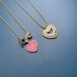 Gold tone detailed necklaces featuring colorful crystal paved love letter and double heart pendants.