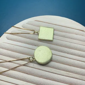 Elegant geometric pendant necklace set featuring square and round textured gold chain designs.