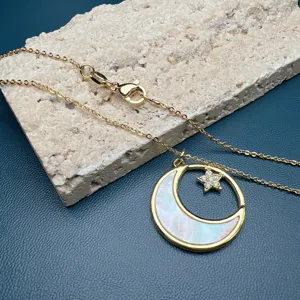 Gros plan d'un collier doré délicat avec un pendentif en nacre et zircon étincelant.