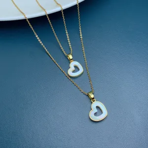 Detail shot of a double-layer gold chain necklace with natural white mother-of-pearl heart pendants.