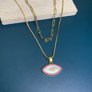 Double layer gold necklace featuring a mother of pearl evil eye pendant with pink cubic zirconia.