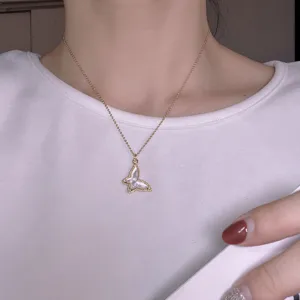 Close-up of gold chain necklace with mother of pearl butterfly pendant detail and delicate look.