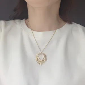 Primo piano di una splendida collana con ciondolo cuore sole dorato e zirconi brillanti.