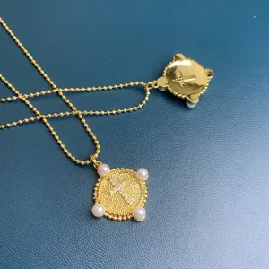 Detailed view of gold rhinestone cross coin pendant necklace with pearl accents, elegant jewelry.