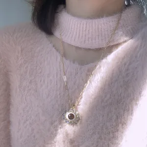 Detailed shot of gold evil eye pendant necklace with sparkling zirconia stones worn on fuzzy sweater.