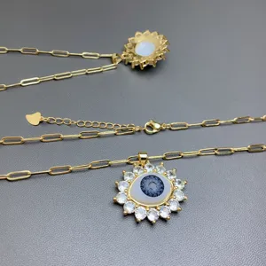 Detail shot of gold paperclip chain necklace with sparkling cubic zirconia evil eye pendant.