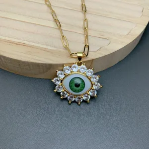 Detailed view of the gold chain necklace with a trendy green evil eye pendant and cubic zirconia.