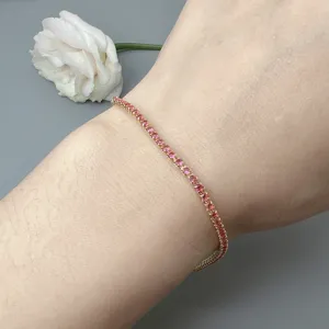 Delicate gold-toned tennis bracelet featuring sparkling pink cubic zirconia stones, detailed shot.