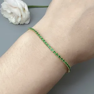 Delicate gold plated tennis bracelet featuring sparkling green cubic zirconia for women.
