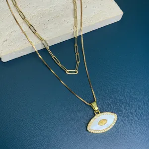 Detail shot of double layer gold necklace featuring mother of pearl evil eye pendant.